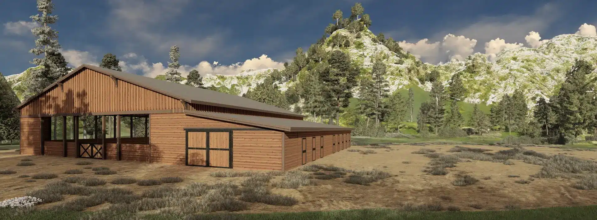 A large wooden barn-style building with wide doors on dry grassland, surrounded by shrubs, pine trees, mountains, and blue sky.