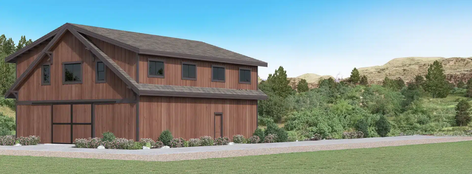 A two-story wooden barn-style house with dark trim near a paved driveway, surrounded by green shrubs, hills, and a clear sky.