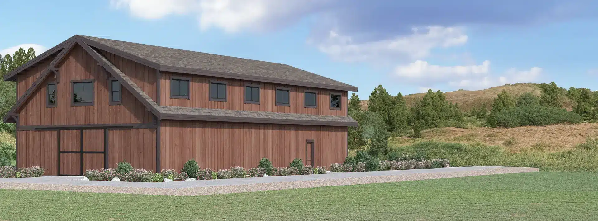 A large brown wooden barn with many windows is surrounded by greenery and grass under a partly cloudy blue sky in a rural landscape.