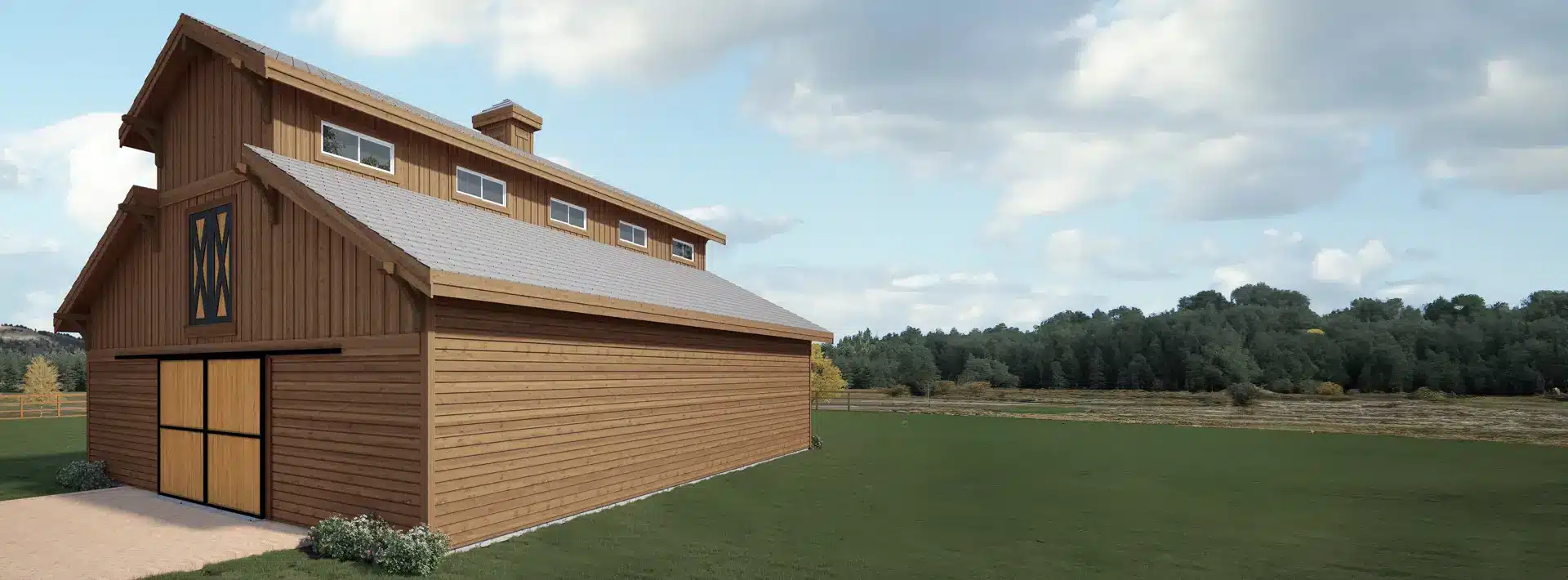 A large wooden barn with a pitched roof and upper windows stands on a grassy field under a partly cloudy sky, trees in distance.