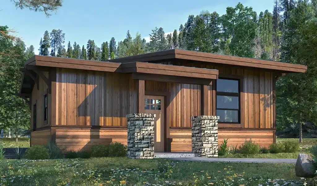 A modern cabin-style house with wooden siding, large windows, flat roof, surrounded by trees, stone entryway, and grassy lawn.