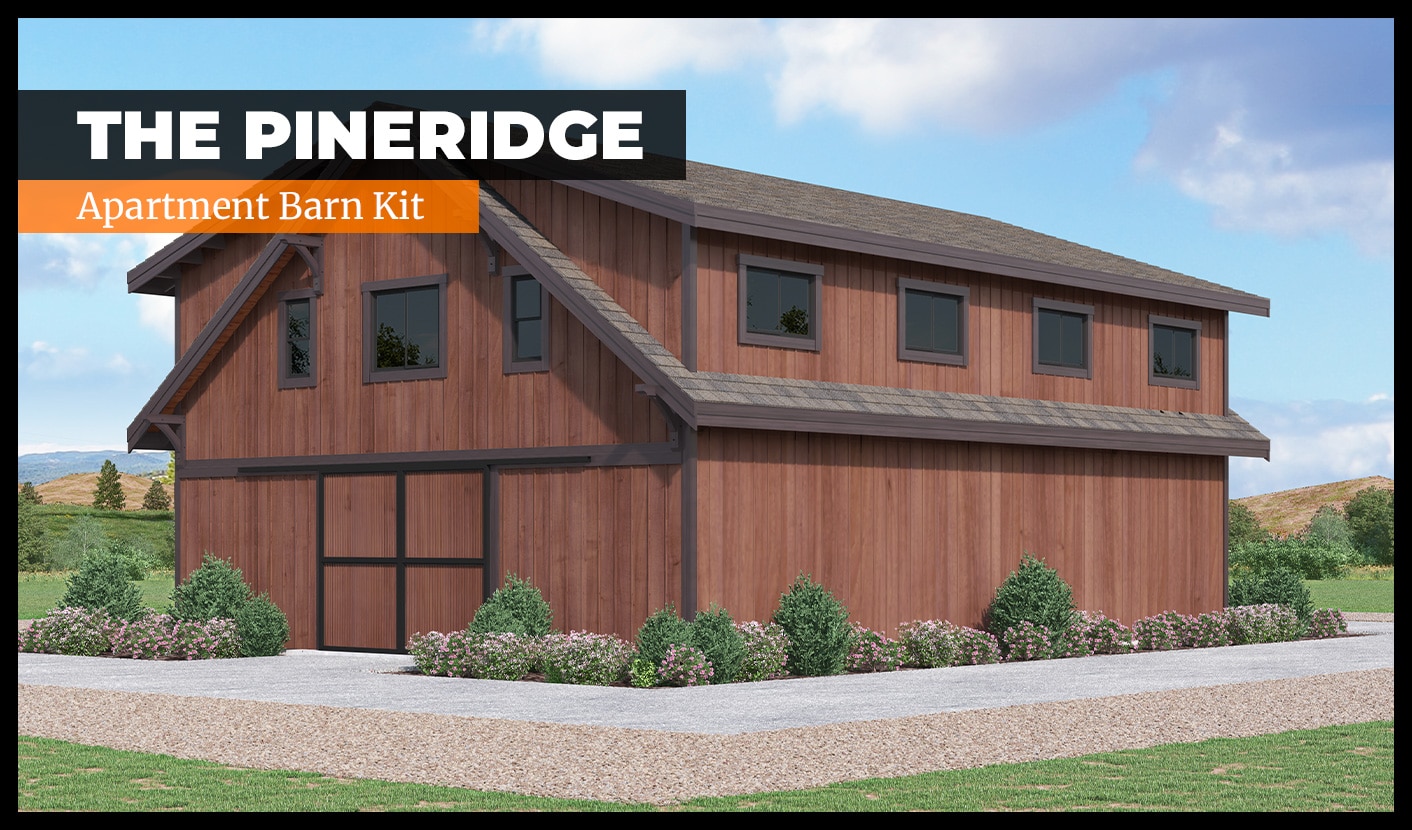 A wooden barn with a modern design is surrounded by bushes and a lawn. The text reads: "The Pineridge - Apartment Barn Kit." The building features large windows and a sloped roof, set against a backdrop of open fields and a partly cloudy sky.