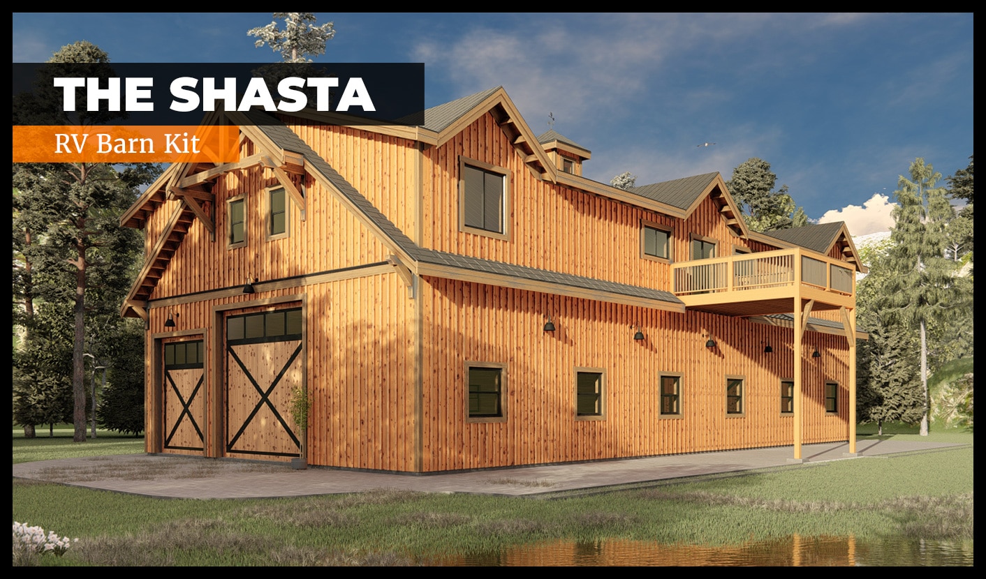 A large, rustic wooden barn with green trim called "The Shasta RV Barn Kit." It has a second-story balcony and multiple windows. Surrounded by trees, it stands near a small pond under a clear blue sky.