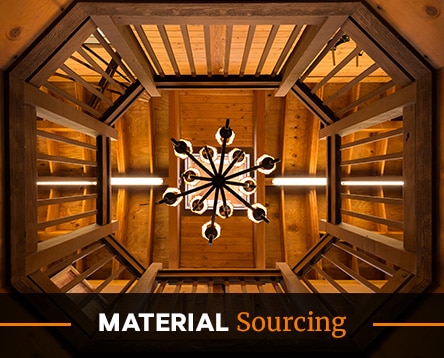 Looking up at a wooden ceiling with a central chandelier, viewed through an octagonal balcony frame. Warm lighting highlights the natural wood tones, reminiscent of cozy cabin kits. At the bottom, the text reads "MATERIAL Sourcing.