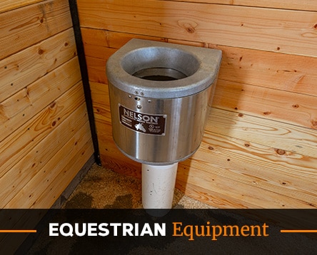 A stainless steel automatic waterer is mounted in the corner of a wooden stable, reminiscent of precision found in garage kits. It features a "Nelson" logo and a white pipe beneath, with the text "Equestrian Equipment" overlaid at the bottom of the image.