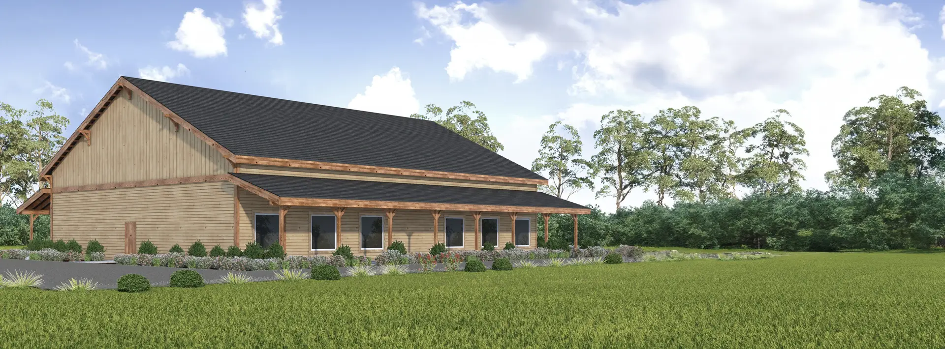 A large wooden barn-style building with a dark roof and covered porch, surrounded by landscaped plants and green grass, with trees in the background under a partly cloudy sky.
