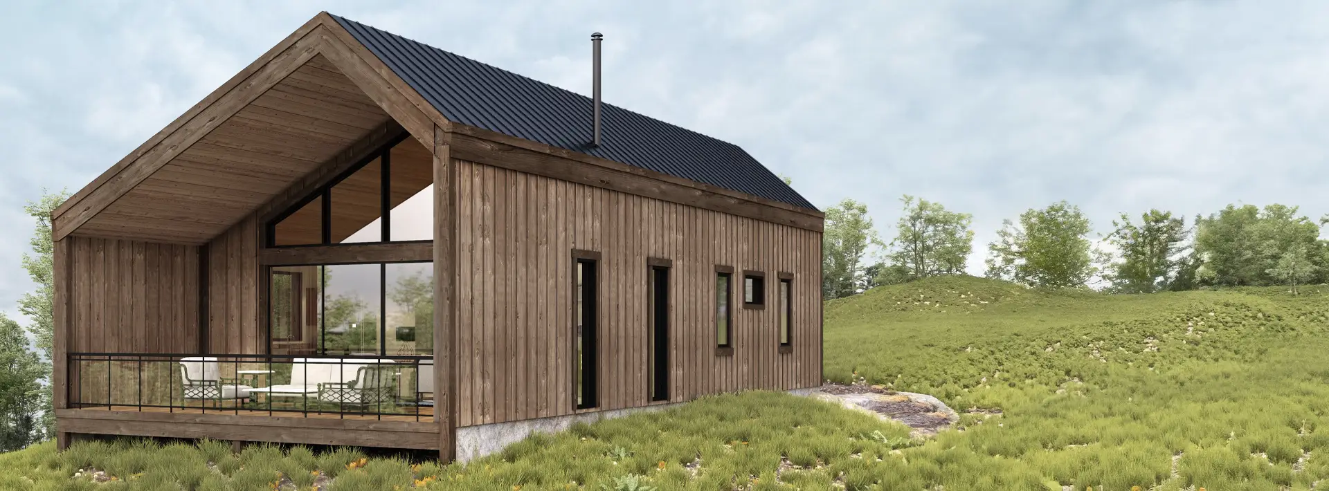 A modern wooden cabin with large windows and a pitched roof stands on a grassy landscape with bushes and distant trees below a cloudy sky.