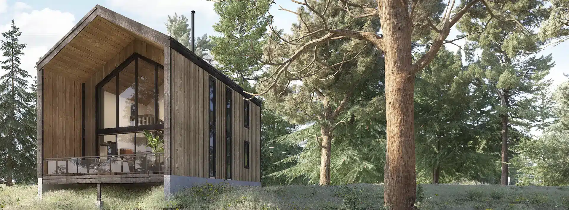 A modern wooden cabin with large glass windows and a balcony is surrounded by tall pine trees and greenery on a gentle forest slope.