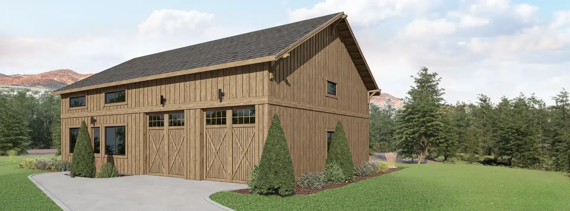 A large wooden barn with a gabled roof, windows, and double doors is surrounded by bushes and trees on a lawn with mountains behind.
