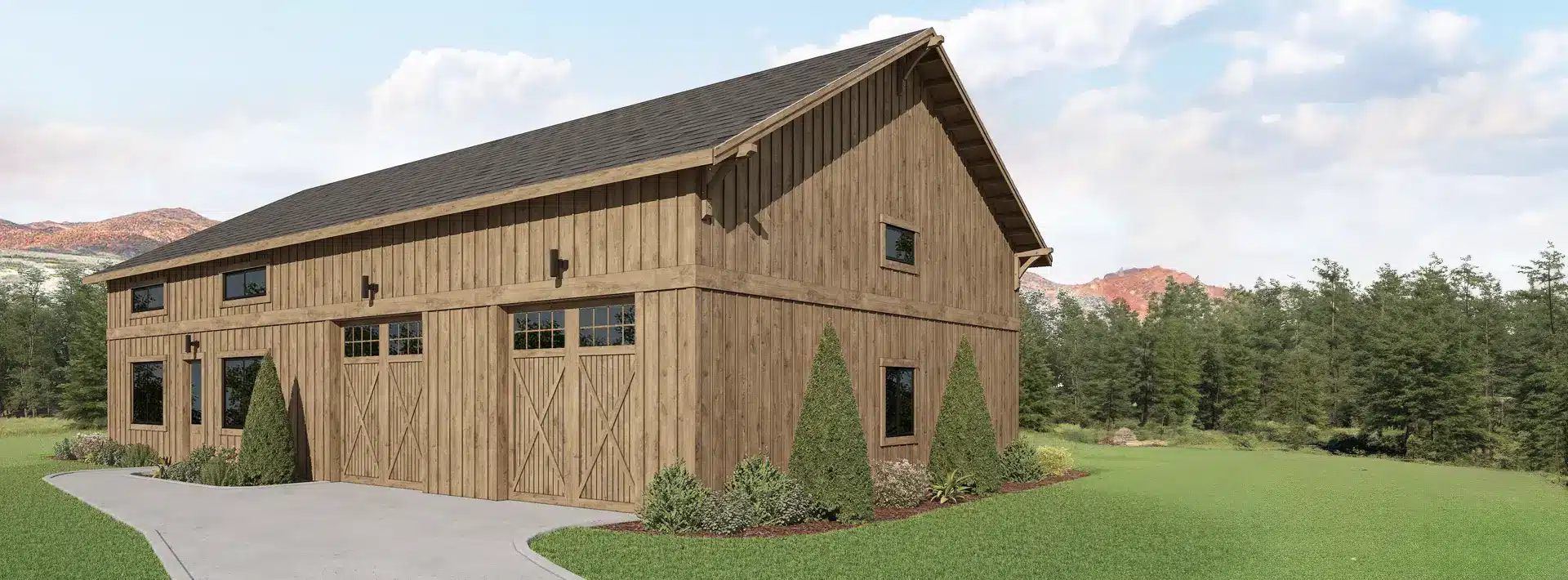 A large wooden barn with sliding doors and windows sits on a concrete driveway, surrounded by greenery and mountains in the background.
