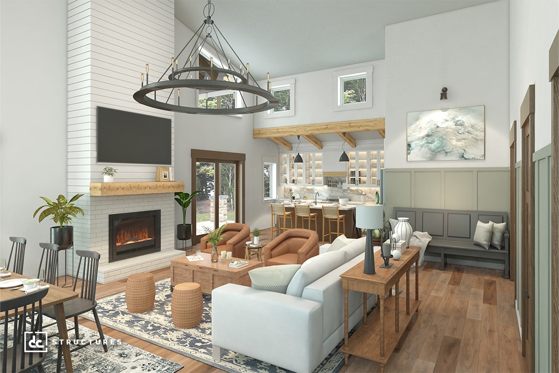 A spacious, modern living room with high ceilings and large windows reminiscent of barndominium kits. It features a fireplace, comfortable seating, and a wooden dining table. The kitchen area boasts a bar with stools, while plants and artwork enhance the decor's charm.