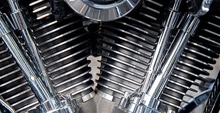 Close-up view of a motorcycle engine showcasing its shiny chrome components and intricate fins, resembling the craftsmanship found in apartment barn kits. The image highlights the mechanical precision and polished surfaces of the engine parts.