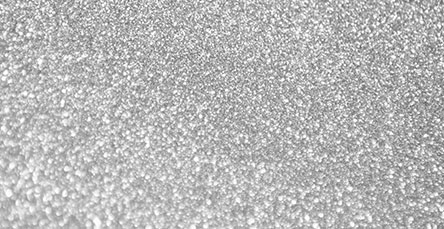 A close-up image showcasing a glittering, silver, and textured surface with small, reflective particles creating a sparkling effect reminiscent of modern apartment barn kits.