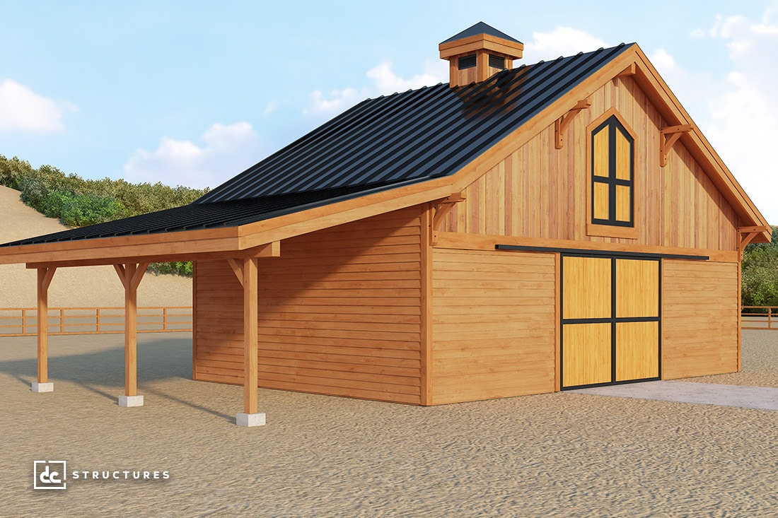 A wooden barn with a pitched black roof and double doors. The building has a large overhang supported by wooden posts. It's set in a sandy area with hills and trees in the background. The DC Structures logo is visible in the bottom left corner.