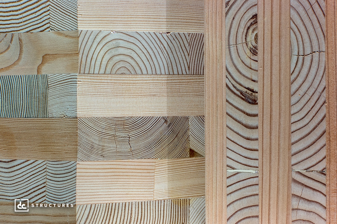 Close-up of various wooden blocks with distinct grain patterns in vertical and horizontal orientations, showcasing alternating light and dark wood tones. Some blocks have concentric circles, while others display linear grain.