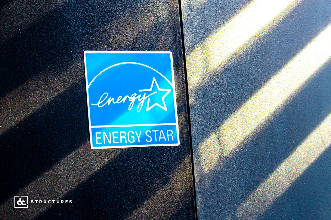 Close-up of a blue sticker on a dark surface with diagonal shadows. The logo features a stylized star and the word energy.