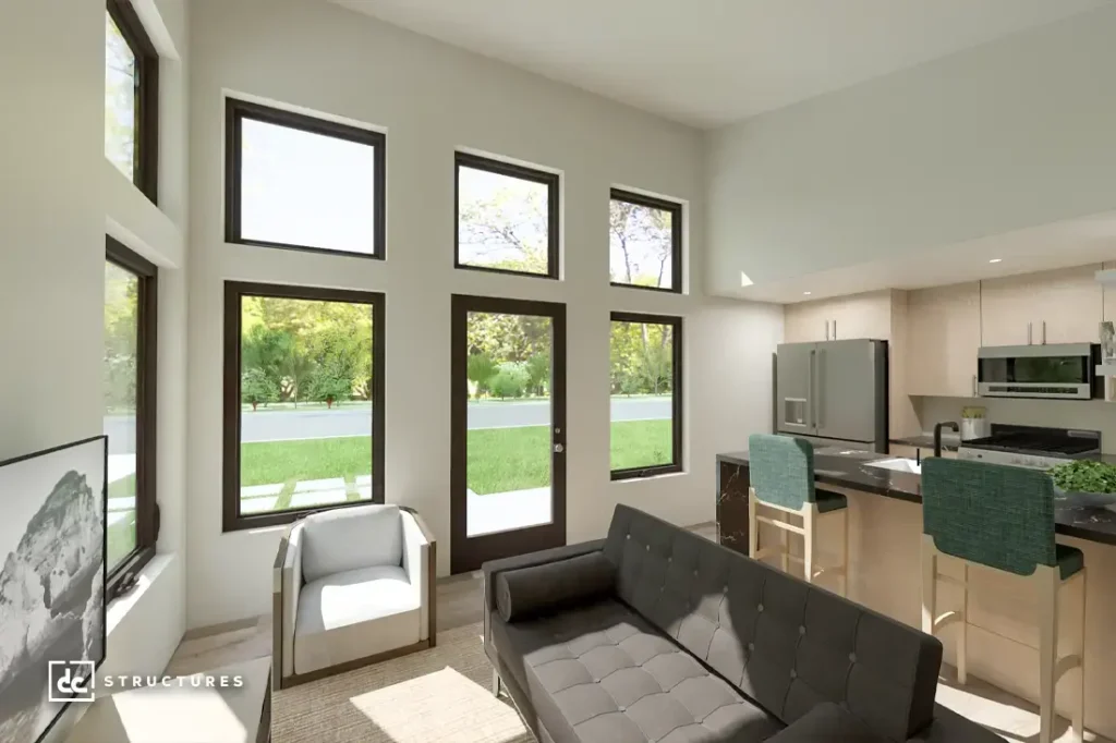 A modern, bright living room and kitchen with large windows, dark sofa, armchair, TV, stainless appliances, and green chairs.