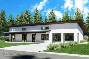 Modern single-story building with a slanted roof, large windows, and white siding, surrounded by grass and tall pine trees under a bright blue sky.