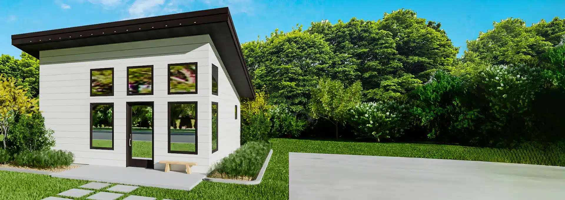A modern tiny house with large windows and a slanted roof stands among lush green trees and grass under a bright blue sky.