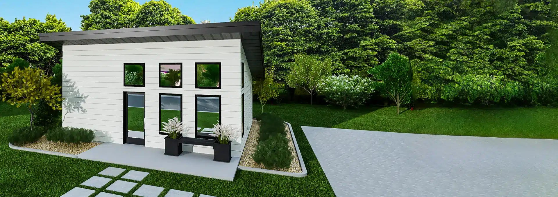 A small modern white house with large windows sits by a paved driveway, surrounded by green grass, bushes, and trees under a blue sky.