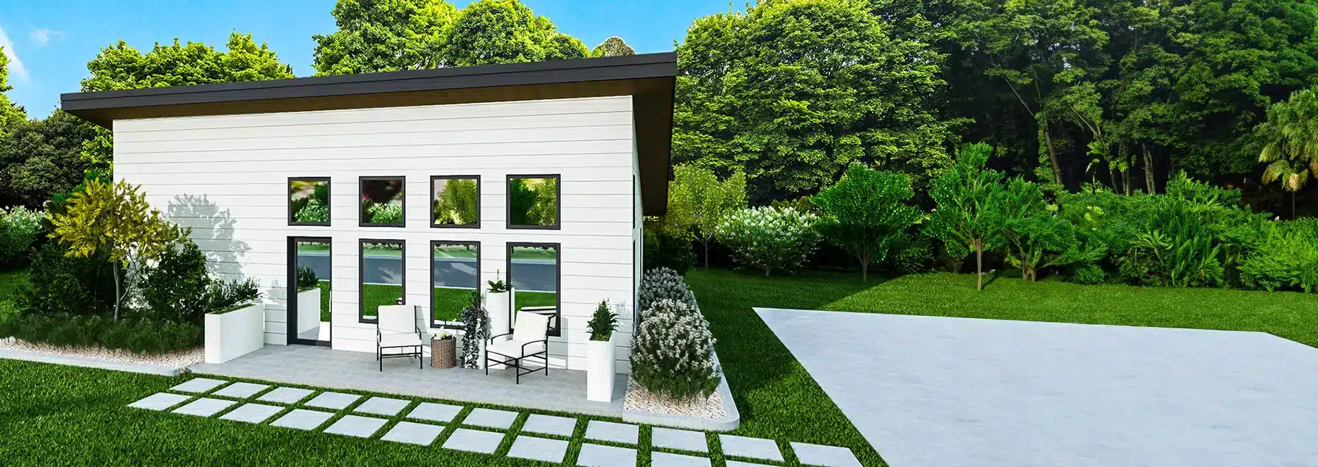 Modern white tiny house with large windows, flat roof, lush grass and trees. Small patio with chairs, table, and tiled walkway.