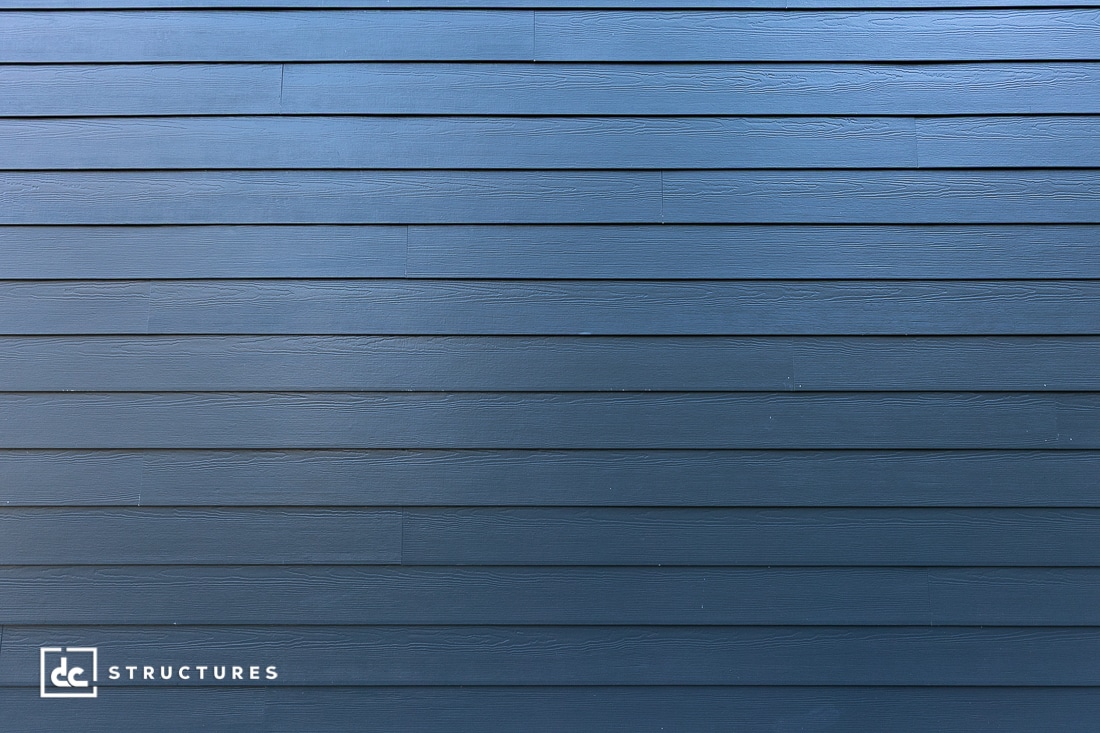 A close-up view of a blue horizontal wooden siding wall with a subtle texture.