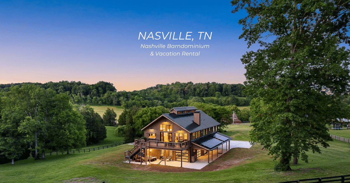 A modern, two-story vacation rental home with large windows and outdoor seating stands amid green fields and trees at sunset in Nashville, TN.